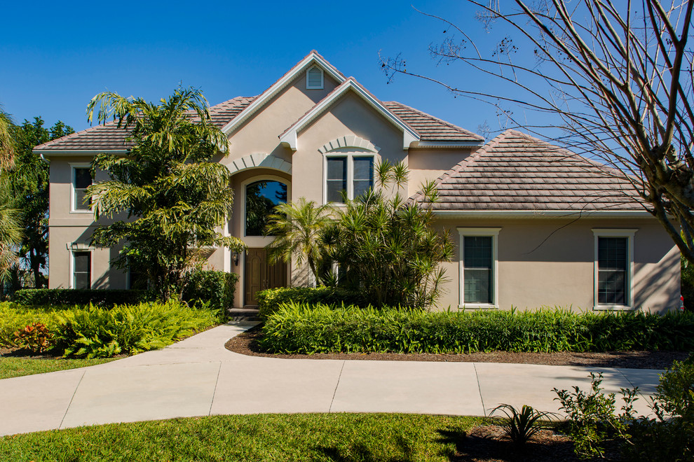 Mid-sized transitional beige two-story stucco exterior home photo in Tampa with a shingle roof