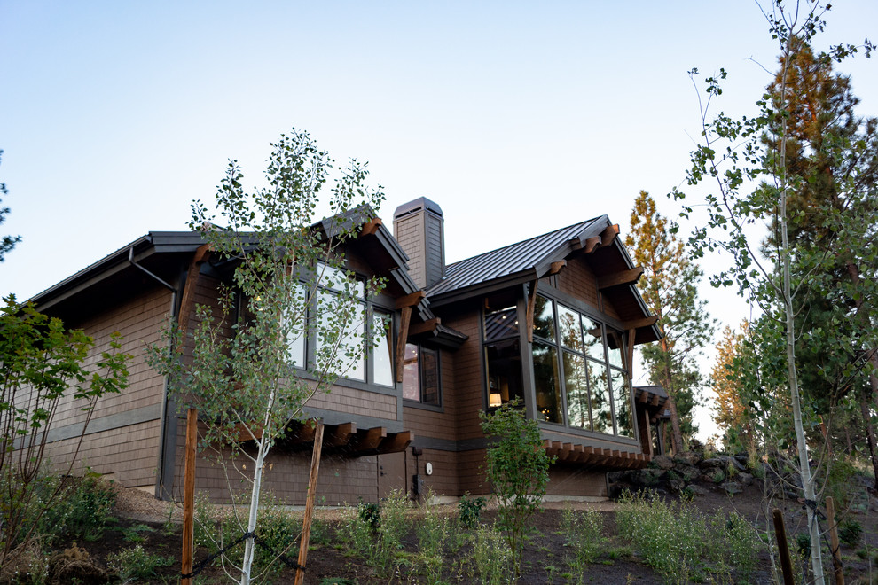 На фото: большой, одноэтажный, коричневый частный загородный дом в стиле рустика с комбинированной облицовкой, двускатной крышей и металлической крышей