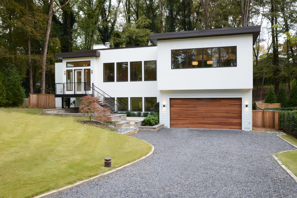 Cette image montre une façade de maison beige minimaliste en stuc de taille moyenne et à un étage avec un toit plat.