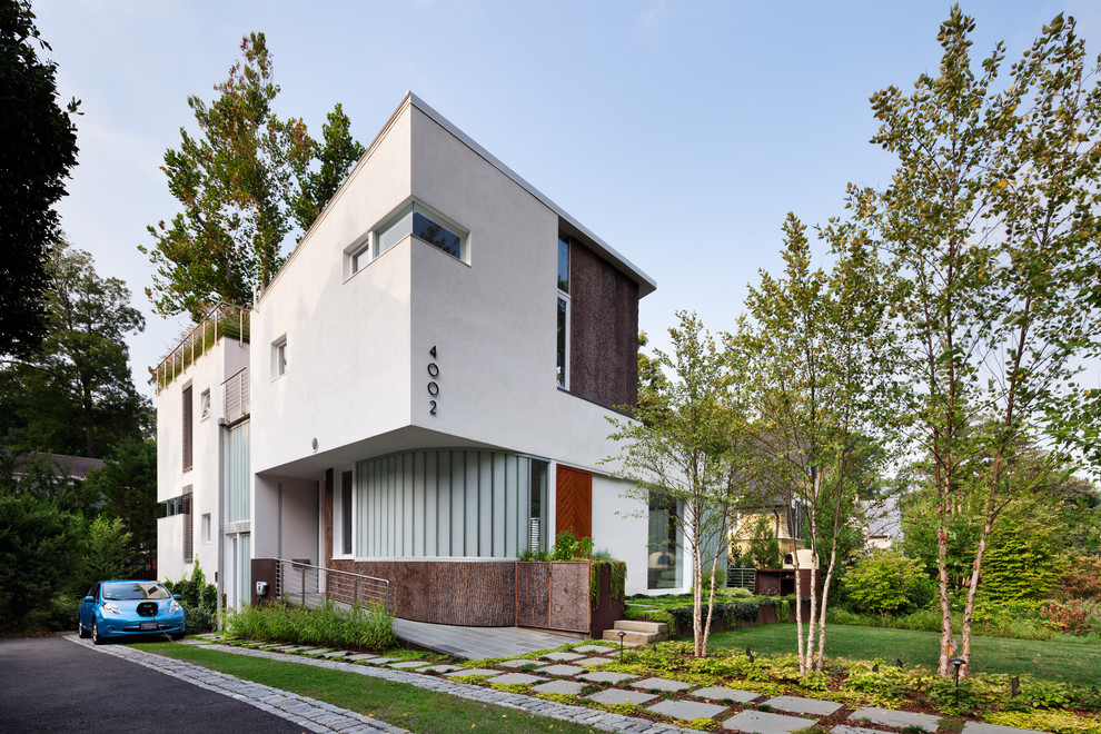 Пример оригинального дизайна: большой, трехэтажный, белый дом в современном стиле с облицовкой из цементной штукатурки и плоской крышей