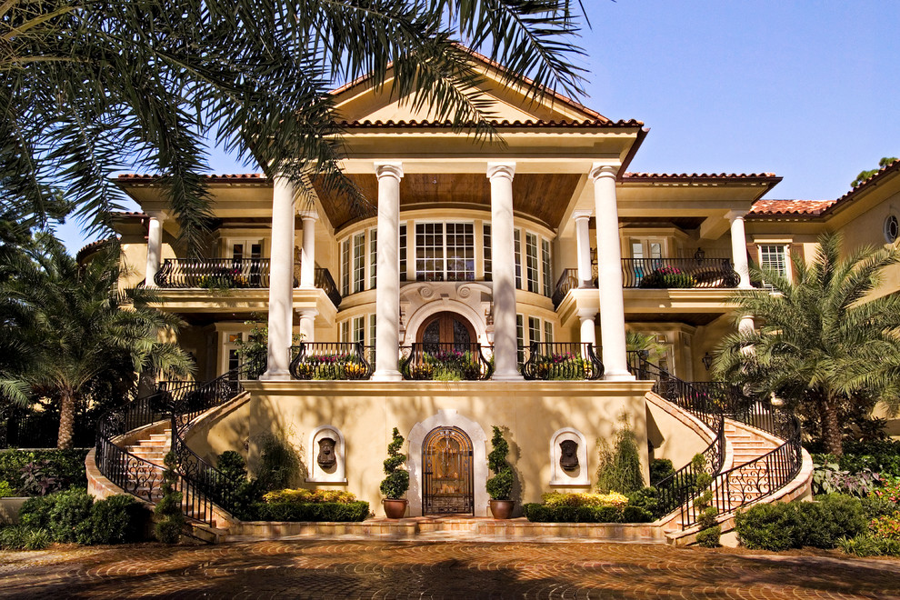 This is an example of a beige mediterranean detached house in Atlanta with three floors and a tiled roof.