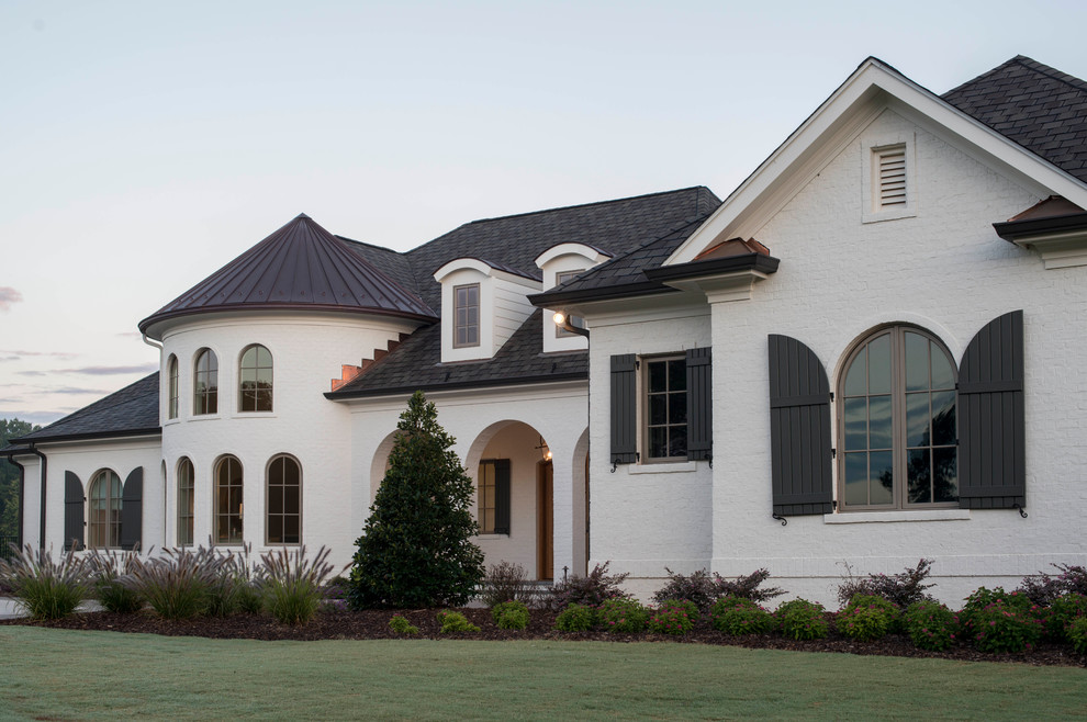 Ejemplo de fachada de casa blanca ecléctica grande de dos plantas con revestimiento de ladrillo, tejado a cuatro aguas y tejado de varios materiales
