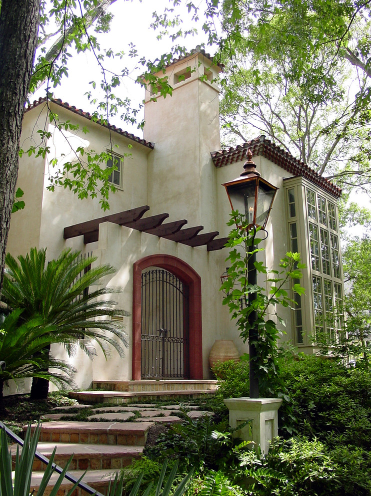 Réalisation d'une façade de maison beige méditerranéenne en stuc de taille moyenne et à un étage avec un toit à quatre pans.