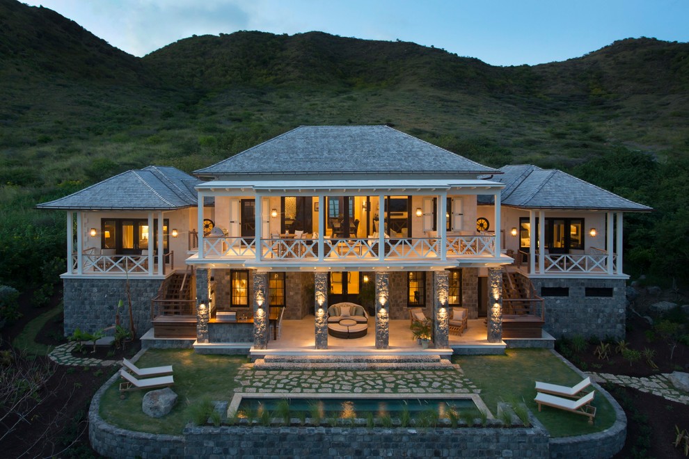 На фото: двухэтажный, бежевый дом в морском стиле с облицовкой из камня и вальмовой крышей с