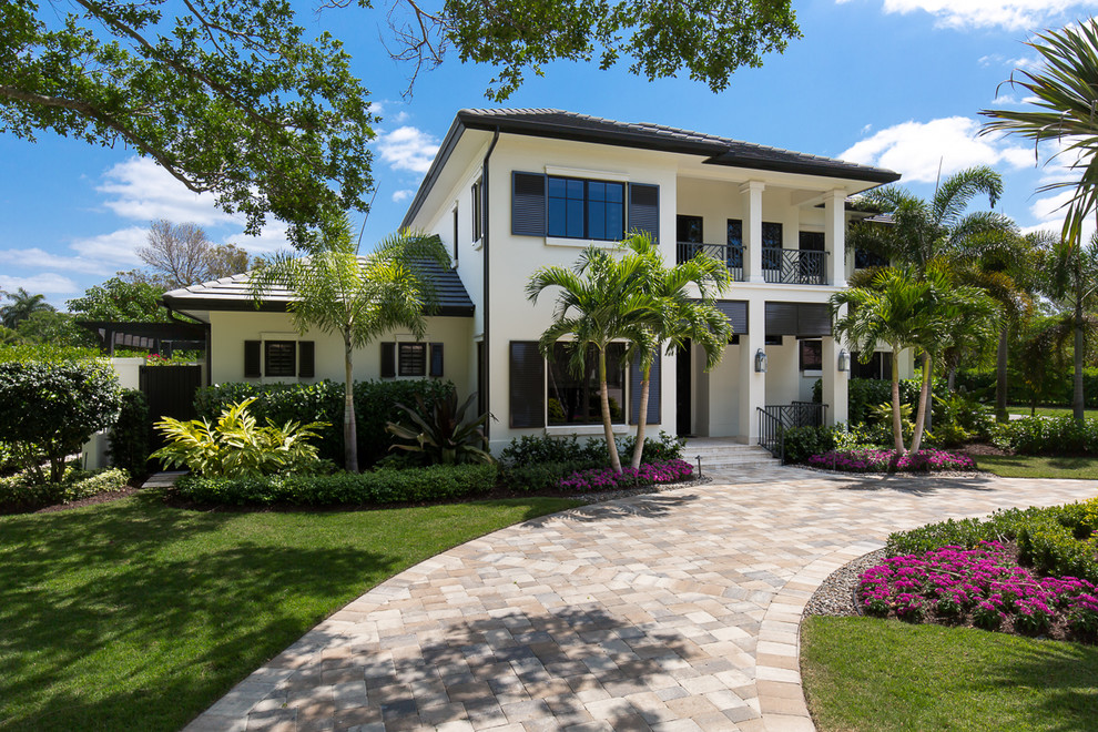 Large island style white two-story stucco exterior home photo in Miami with a hip roof