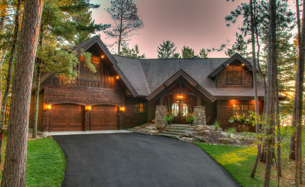 На фото: большой, деревянный, коричневый, двухэтажный частный загородный дом в стиле рустика с двускатной крышей и крышей из гибкой черепицы