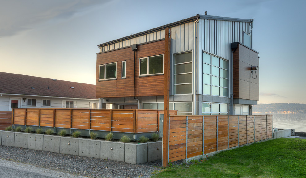 На фото: двухэтажный, серый, маленький частный загородный дом в современном стиле с облицовкой из металла, односкатной крышей и металлической крышей для на участке и в саду
