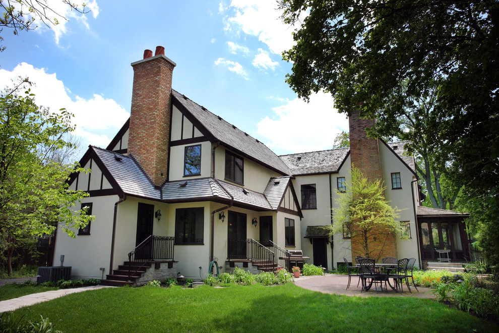 This is an example of a large and beige classic two floor render house exterior in Chicago with a pitched roof.