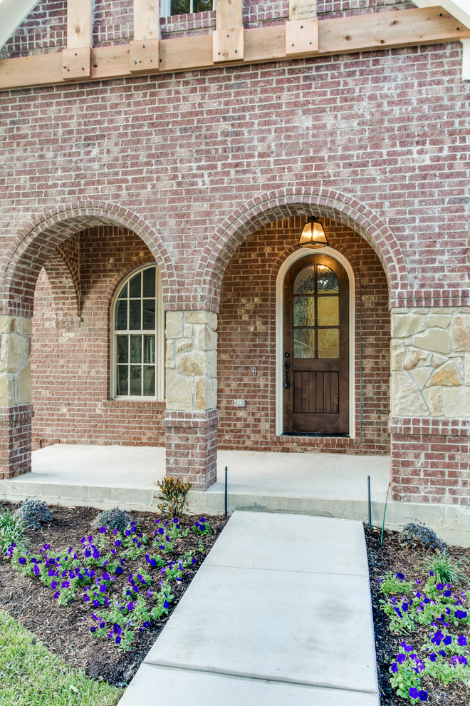 Medium sized and red traditional two floor brick house exterior in Dallas with a pitched roof.