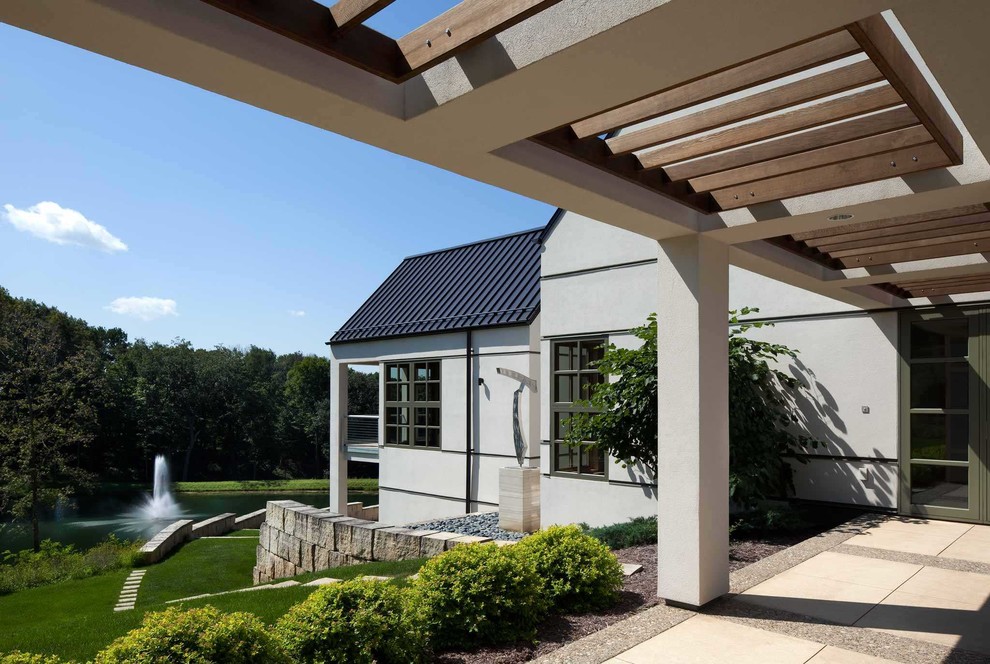 Diseño de fachada de casa blanca contemporánea extra grande de una planta con revestimiento de estuco, tejado a dos aguas y tejado de metal