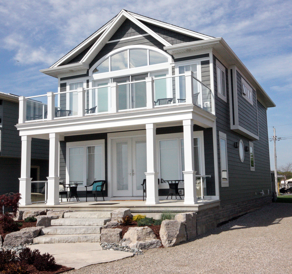 На фото: маленький, двухэтажный, серый дом в морском стиле с облицовкой из ЦСП и двускатной крышей для на участке и в саду с