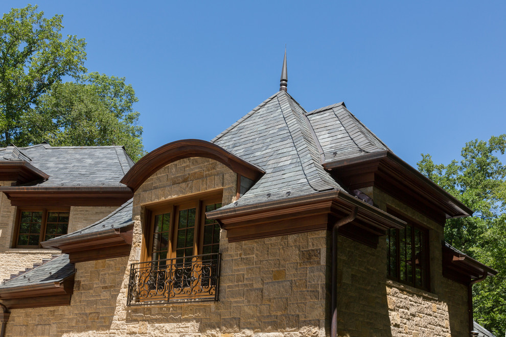 Réalisation d'une très grande façade de maison beige tradition en pierre à un étage avec un toit à quatre pans.