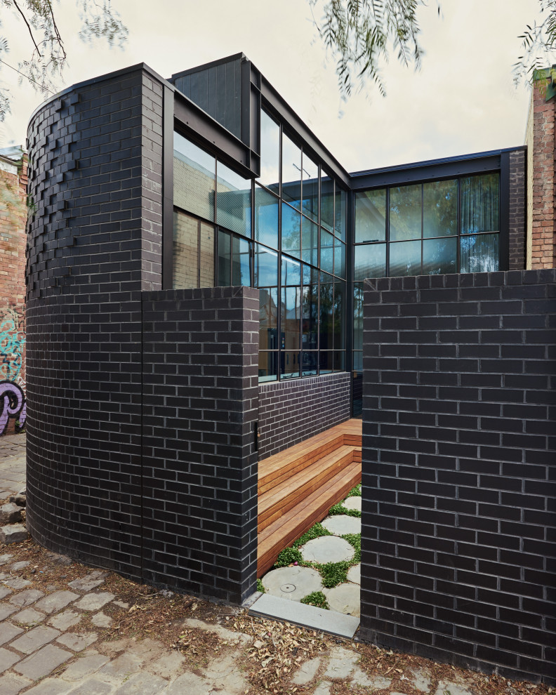 Example of a mid-sized trendy black one-story brick exterior home design in Melbourne with a metal roof