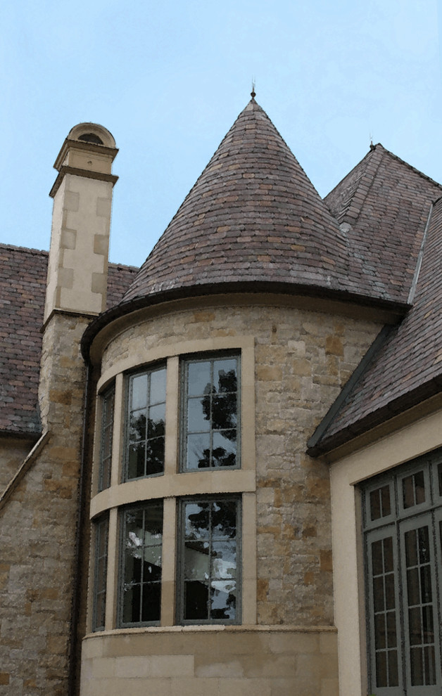 Cette image montre une très grande façade de maison beige traditionnelle en stuc à un étage avec un toit en tuile.