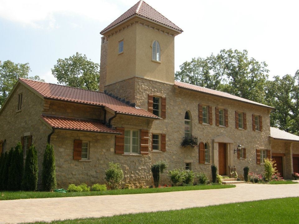На фото: трехэтажный, коричневый, большой частный загородный дом в средиземноморском стиле с облицовкой из камня и черепичной крышей с