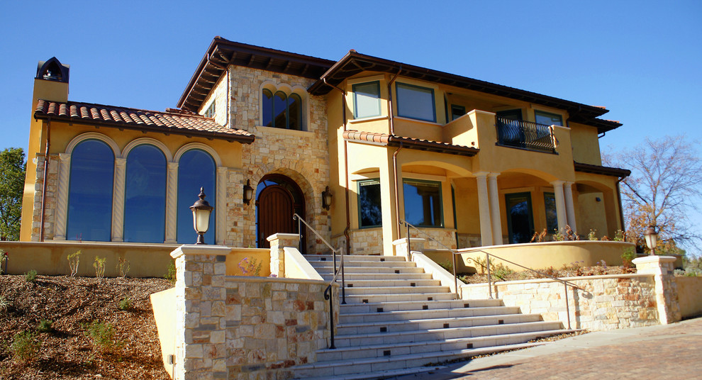 Стильный дизайн: двухэтажный, желтый, большой дом в средиземноморском стиле с облицовкой из камня - последний тренд