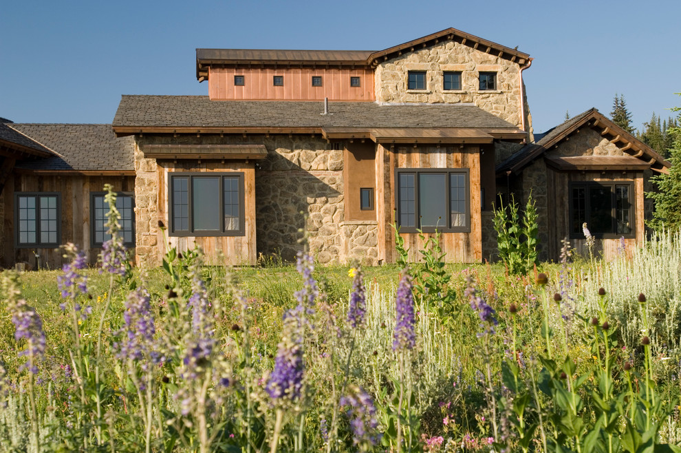This is an example of a rustic house exterior in Other with stone cladding.