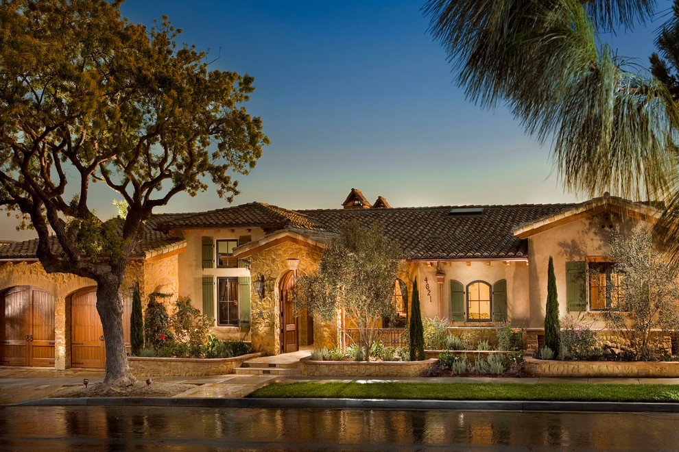 This is an example of a medium sized and beige mediterranean bungalow house exterior in Orange County.