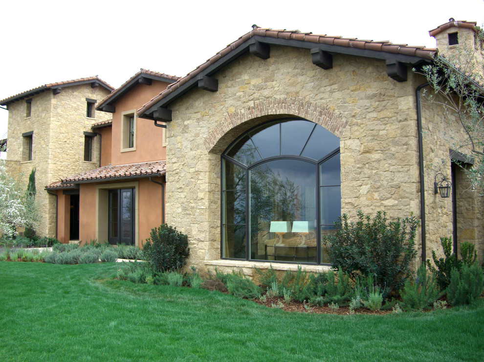 Immagine della facciata di una casa mediterranea con rivestimento in pietra