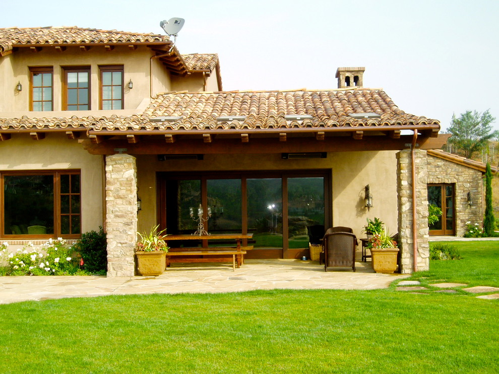 Diseño de fachada de casa beige mediterránea grande de dos plantas con revestimiento de estuco y tejado de teja de barro