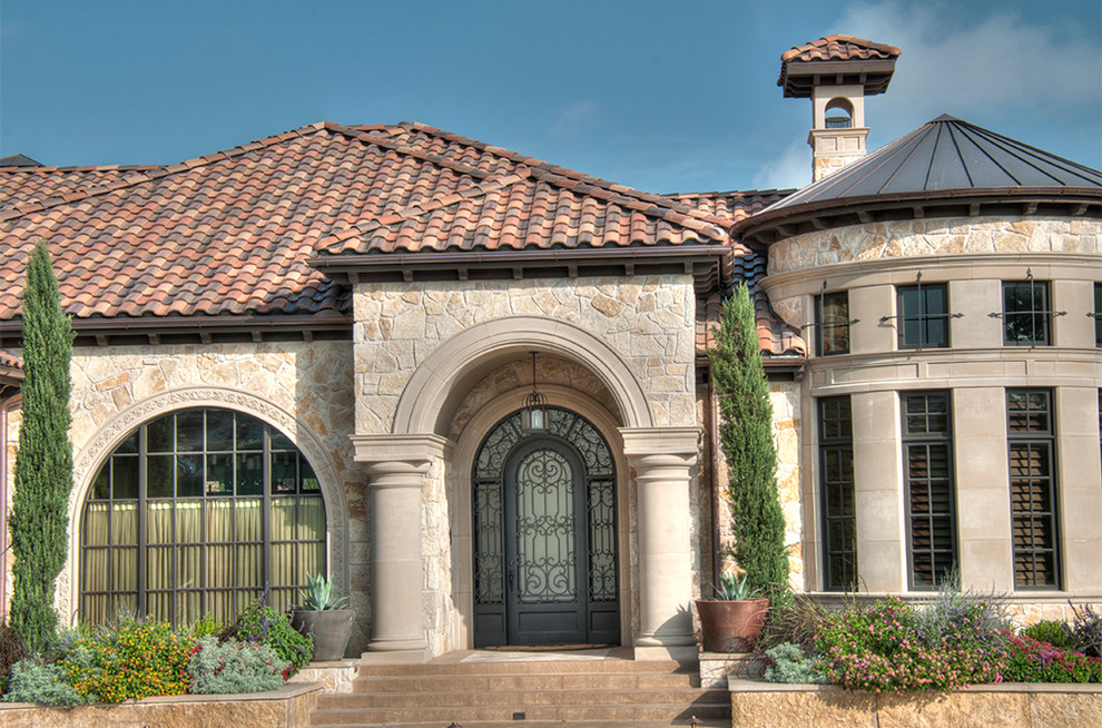 Стильный дизайн: огромный, двухэтажный, бежевый дом в классическом стиле с облицовкой из камня и вальмовой крышей - последний тренд
