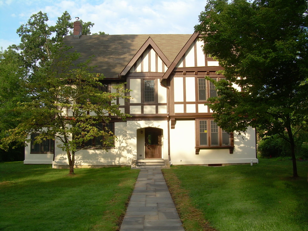 Exemple d'une grande façade de maison beige chic en stuc à un étage avec un toit en shingle.