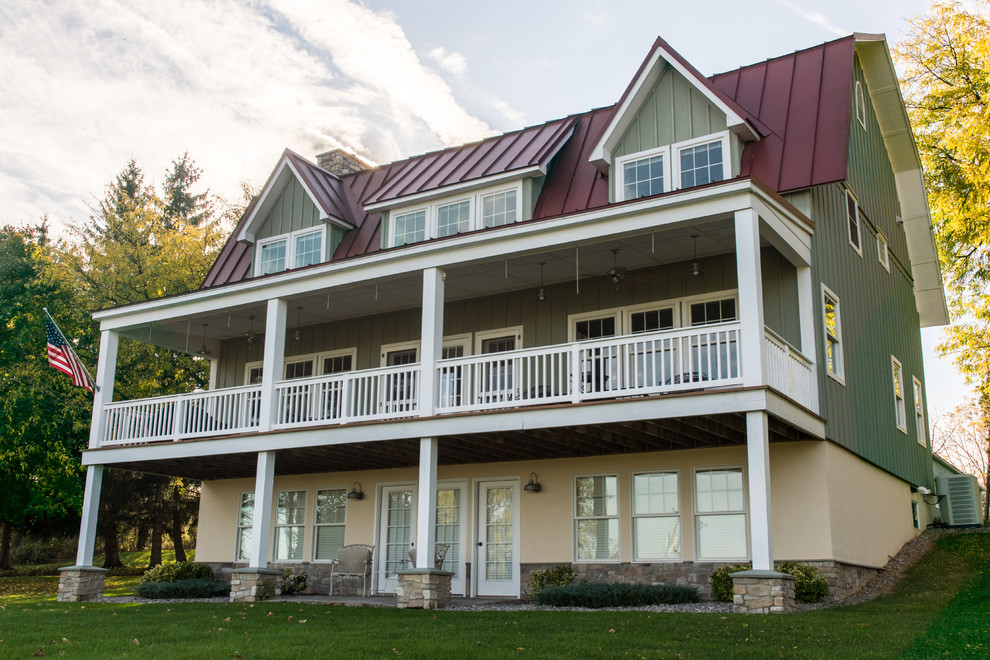 Foto della facciata di una casa grande verde country a tre piani con rivestimento in legno e tetto a mansarda