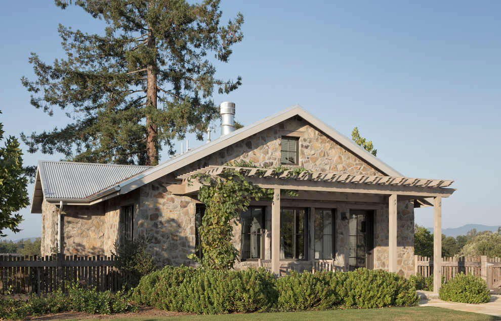 Diseño de fachada de casa campestre de dos plantas con revestimiento de piedra, tejado a dos aguas y tejado de metal