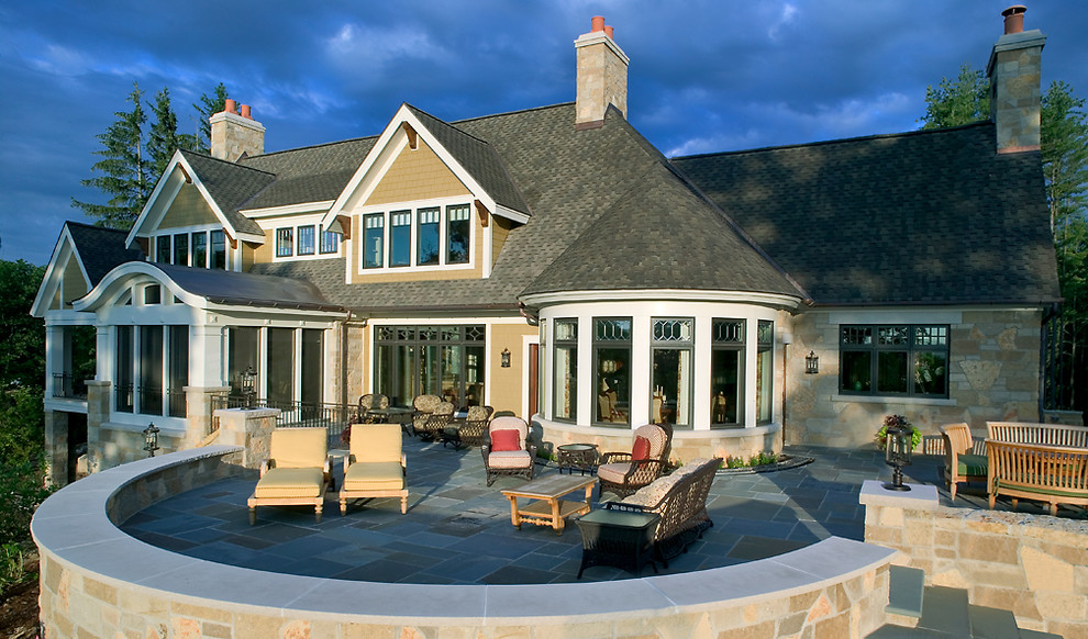 Inspiration for a huge transitional beige three-story stone exterior home remodel in Grand Rapids with a clipped gable roof