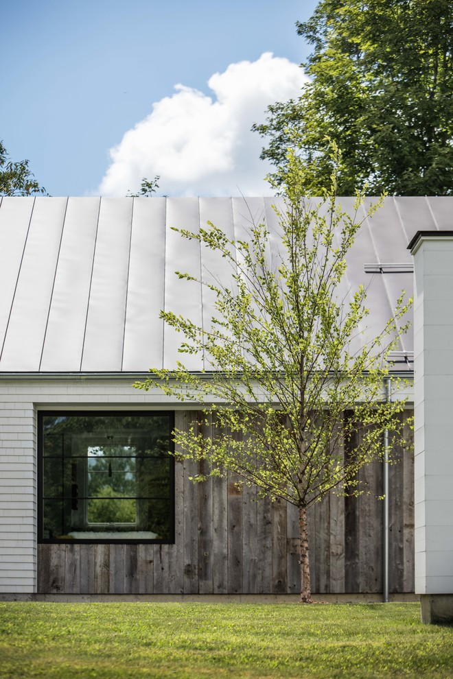 Diseño de fachada de casa blanca contemporánea grande de dos plantas con revestimiento de madera, tejado de un solo tendido y tejado de metal