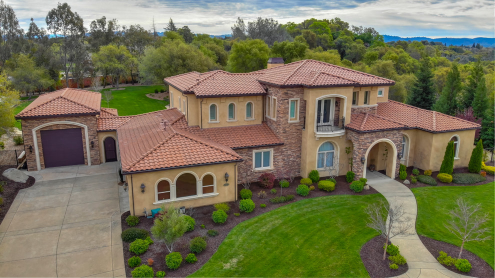 Large tuscan orange two-story stucco house exterior photo in Sacramento with a hip roof and a tile roof