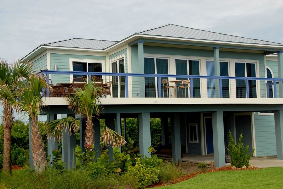 Cette image montre une grande façade de maison bleue marine en bois à un étage avec un toit à quatre pans et un toit en métal.