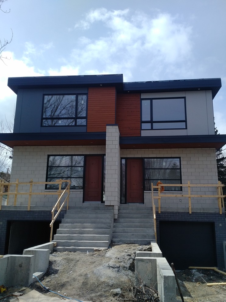 Diseño de fachada de casa bifamiliar gris actual con revestimiento de hormigón