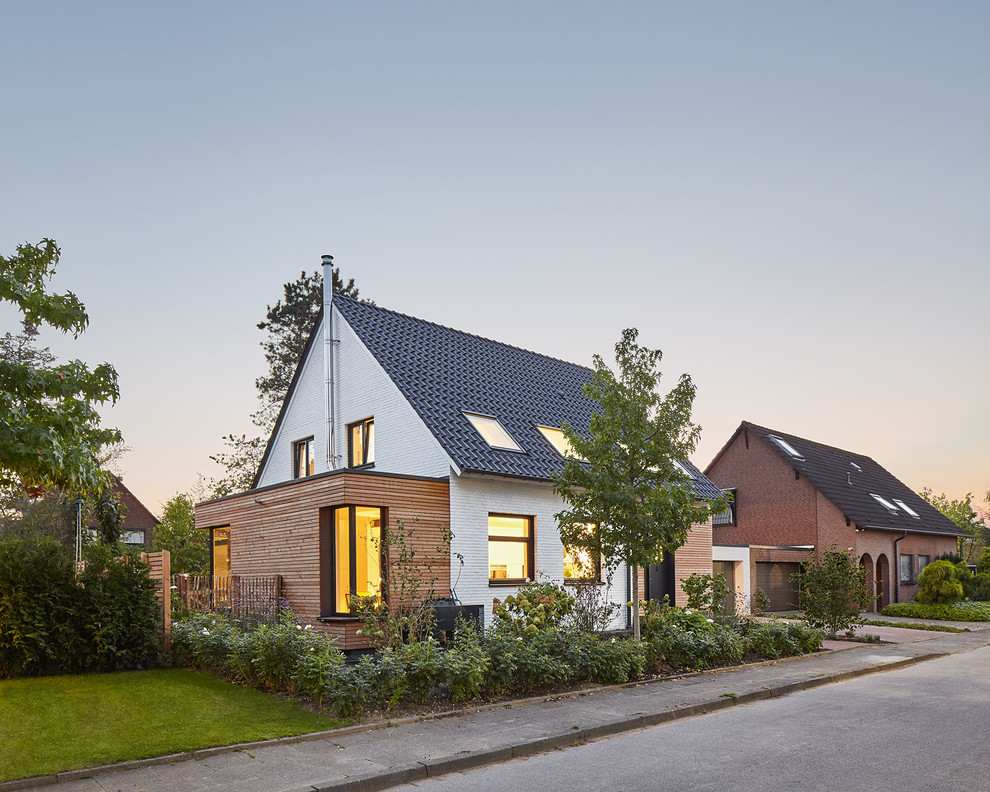 This is an example of a medium sized and white modern bungalow brick house exterior in Dusseldorf with a pitched roof.