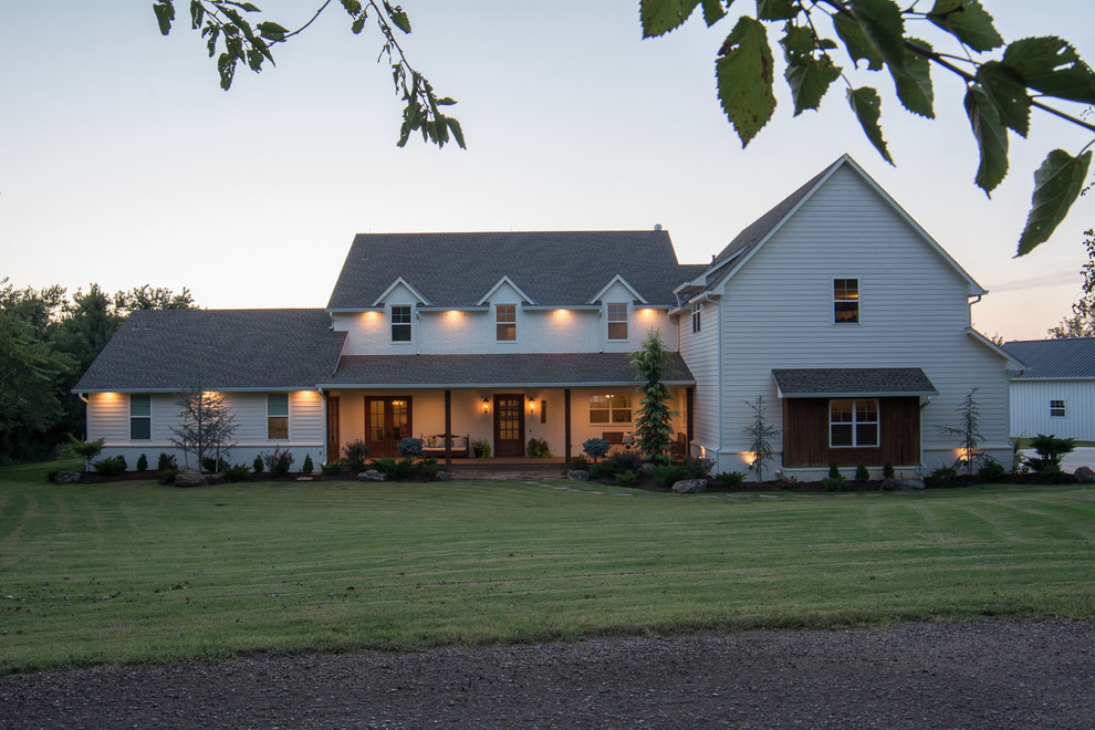 Réalisation d'une grande façade de maison blanche champêtre à un étage avec un revêtement en vinyle, un toit à deux pans et un toit en shingle.
