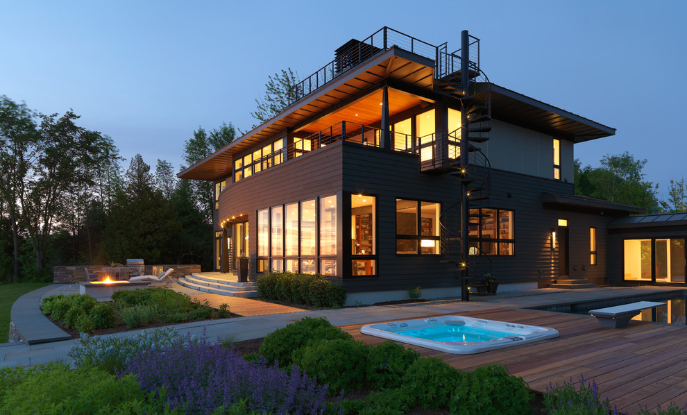 Cette photo montre une façade de maison marron moderne à un étage avec un revêtement mixte et un toit à quatre pans.