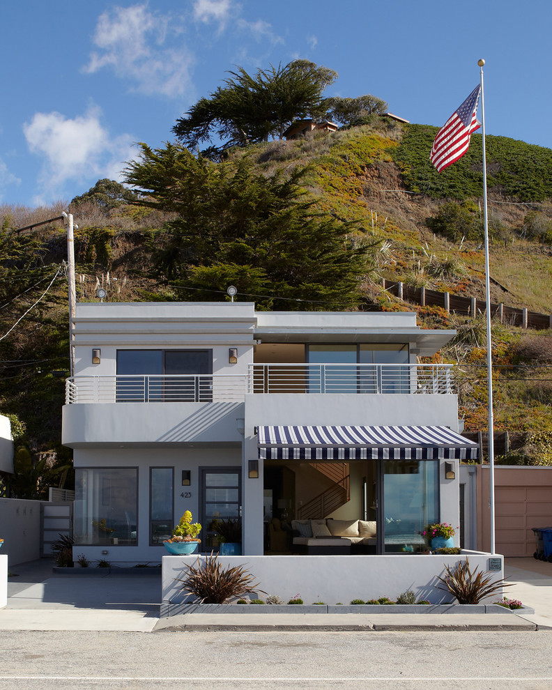 На фото: маленький, двухэтажный, серый частный загородный дом в морском стиле с плоской крышей, облицовкой из цементной штукатурки и металлической крышей для на участке и в саду с