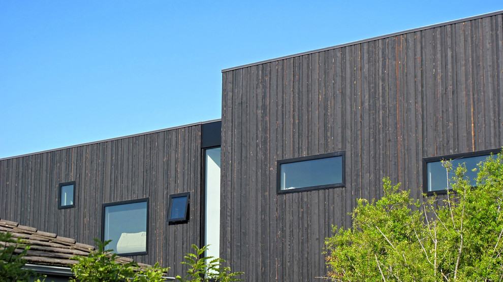 This is an example of a large and black modern two floor house exterior in San Francisco with wood cladding.
