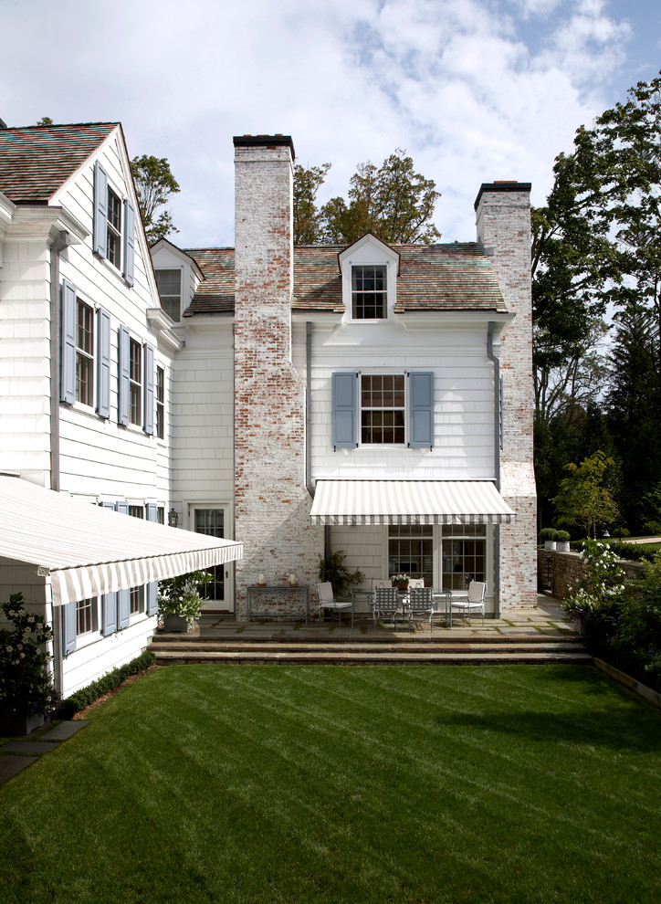 White and large traditional two floor house exterior in New York with a pitched roof and wood cladding.