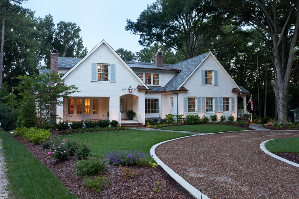 На фото: кирпичный, белый дом в классическом стиле с двускатной крышей