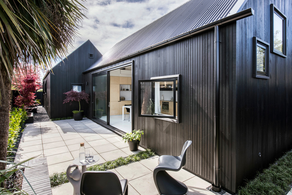Photo of a small and black contemporary bungalow house exterior in Christchurch with wood cladding and a pitched roof.