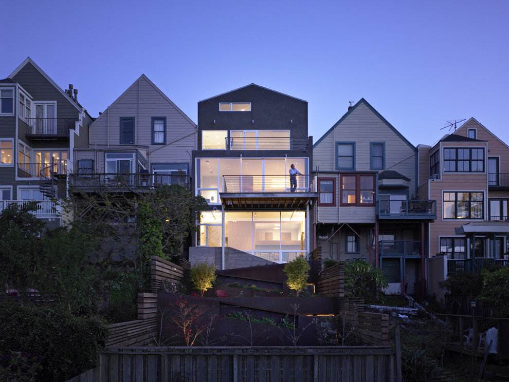 Immagine della facciata di una casa contemporanea a tre piani con terreno in pendenza