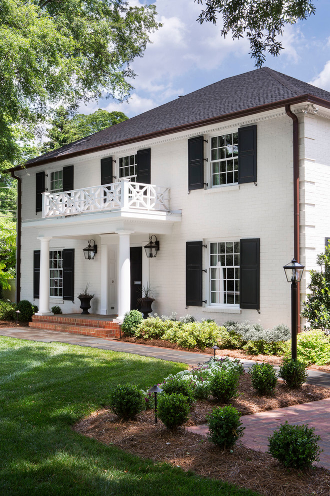 This is an example of a white classic two floor brick house exterior in Charlotte with a hip roof.