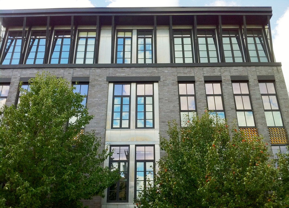 Ejemplo de fachada gris moderna extra grande de tres plantas con revestimiento de ladrillo y tejado a dos aguas
