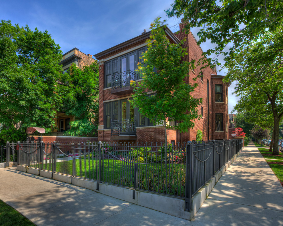 Large and red classic brick detached house in Chicago with a flat roof, three floors and a mixed material roof.