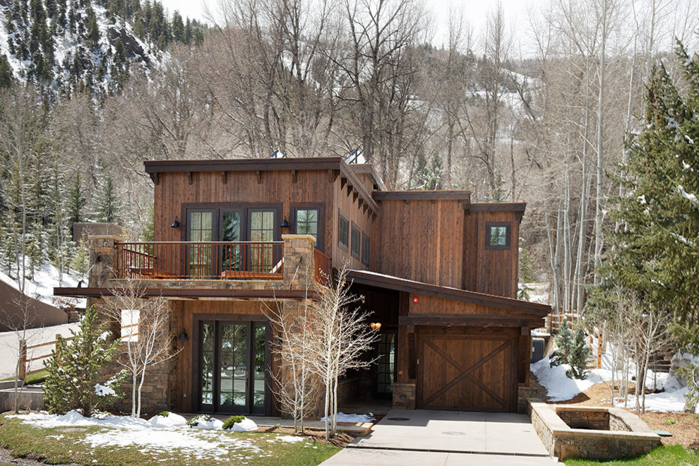 Idée de décoration pour une grande façade de maison marron minimaliste en pierre à deux étages et plus avec un toit plat.