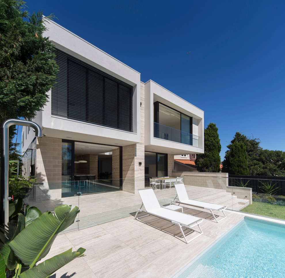 Large and white contemporary two floor house exterior in Sydney with stone cladding and a flat roof.