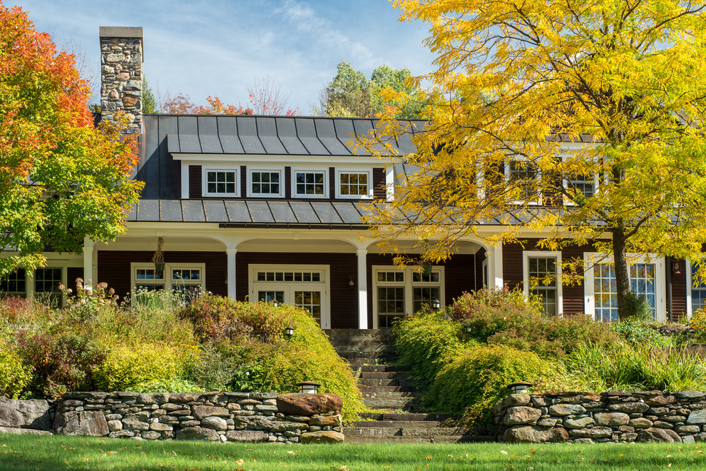 Foto della facciata di una casa grande marrone country a due piani con rivestimento in legno e tetto a capanna