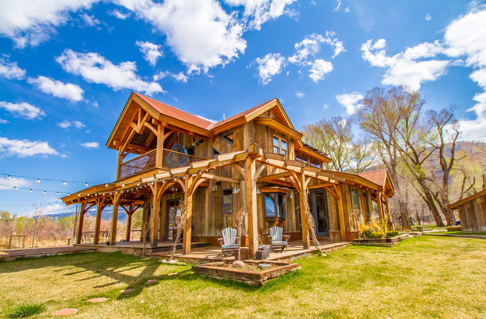 Immagine della villa marrone rustica a due piani di medie dimensioni con rivestimento in legno, tetto a padiglione e copertura in metallo o lamiera