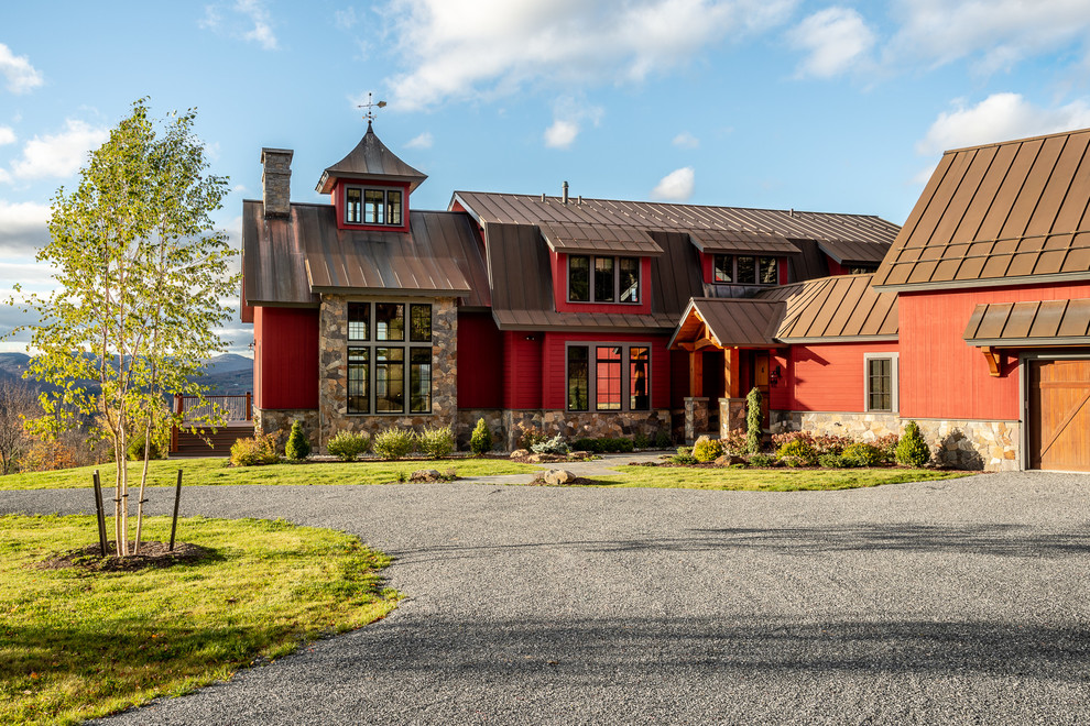 Foto della villa rossa country a due piani con rivestimenti misti, tetto a capanna e copertura in metallo o lamiera